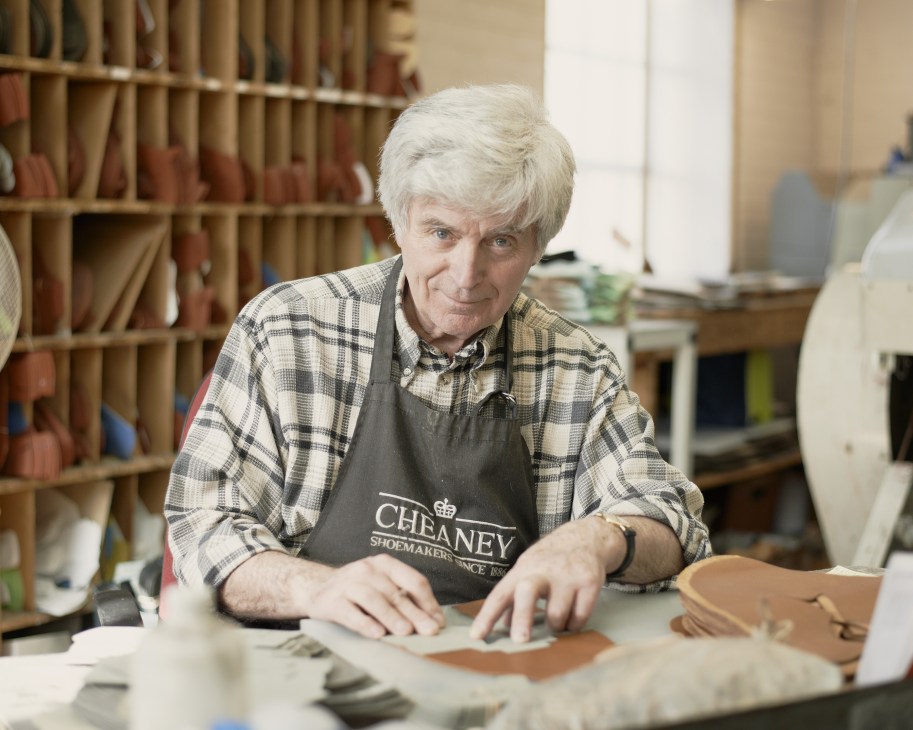 Craftsman in Joseph Cheaney & Sons apron working with leather at a workbench in the Closing Room.