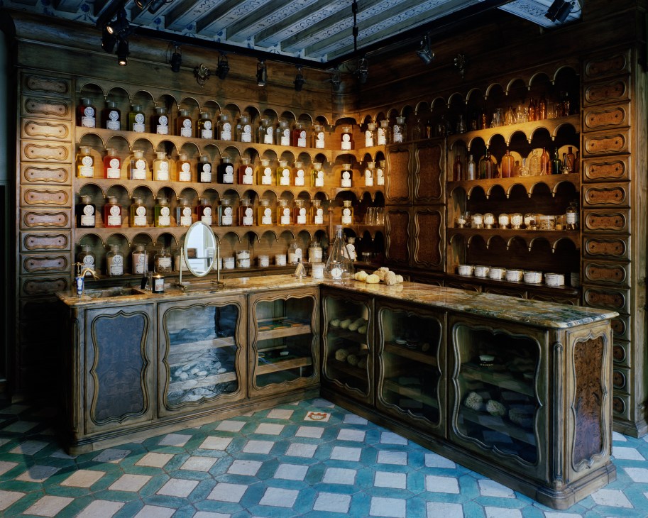 Interior of Officina di Santa Maria Novella pharmacy with wooden display cabinets and shelves of apothecary jars.