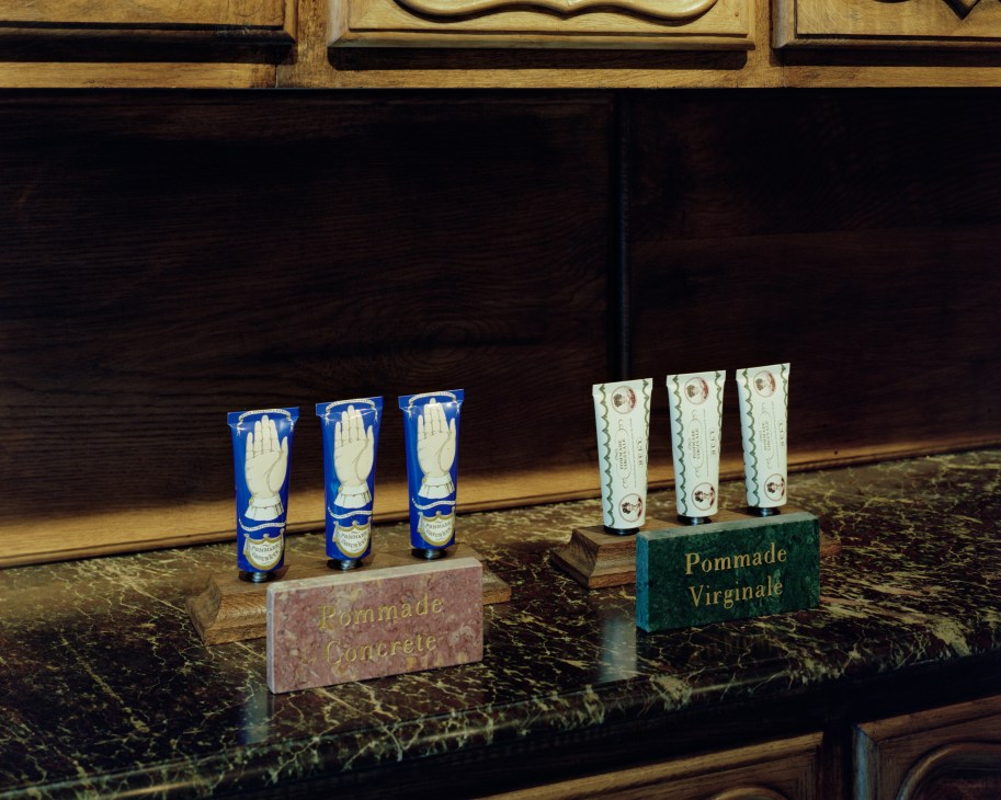Display of blue and cream colored pomade bottles with hand-shaped labels at Buly 1803 Paris apothecary.