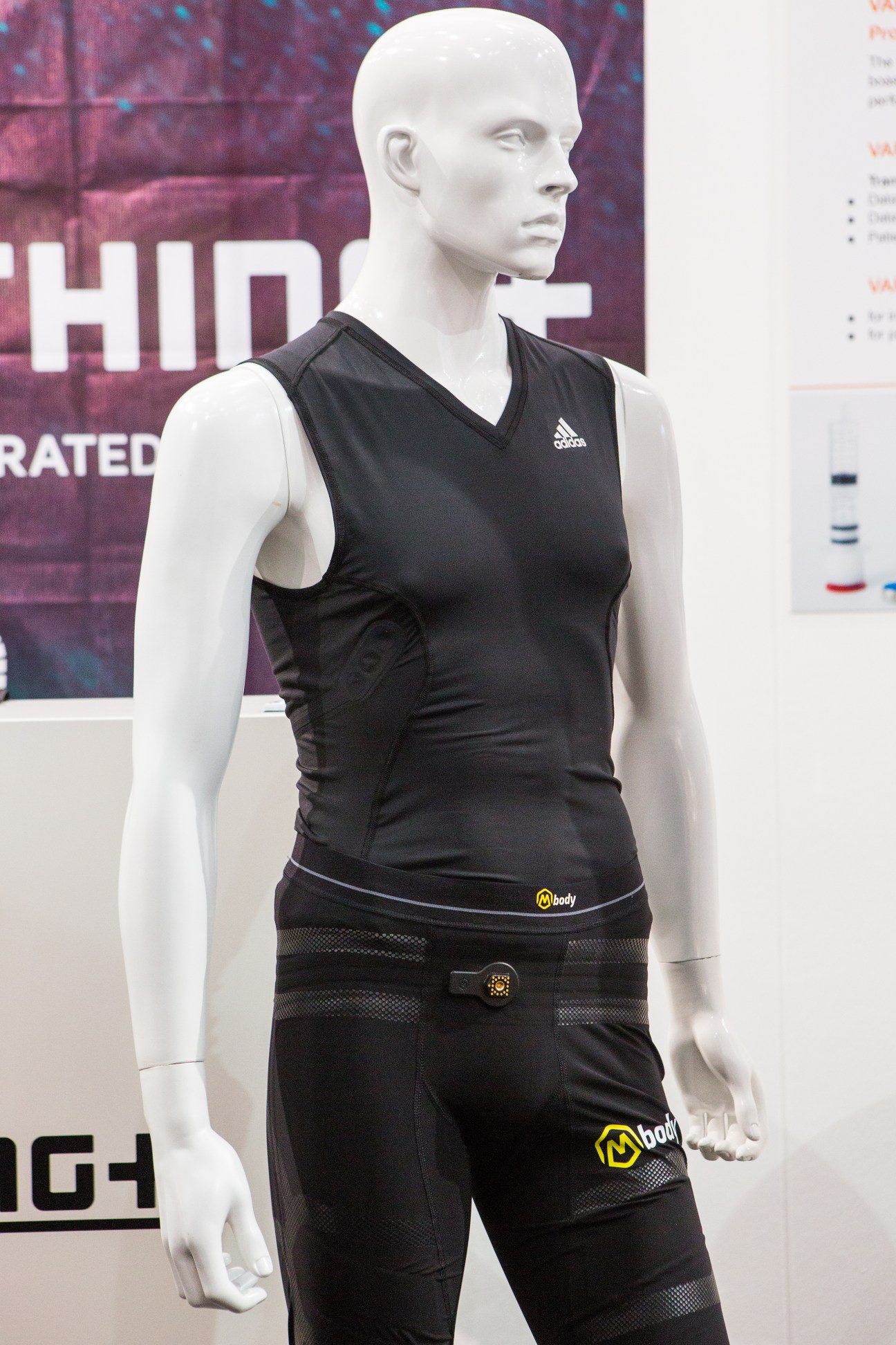 Mannequin wearing black Adidas tank top and biometric sensor shorts with yellow branding at Medica trade fair