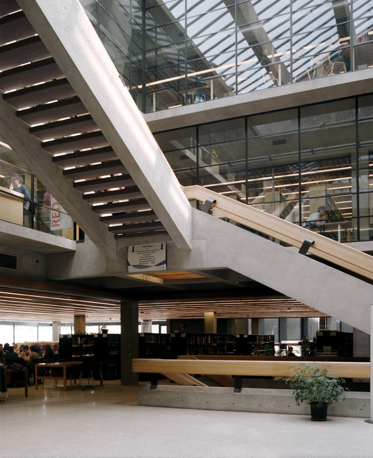 Interior of Bata Library showing brutalist concrete staircase with skylights and wooden railings above library spaces.