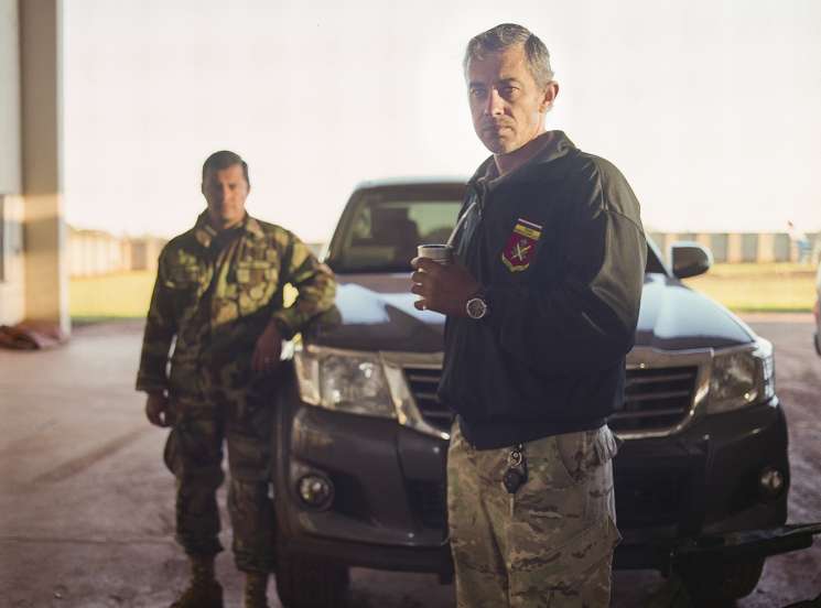 Captain Oscar Chamorro, head of Senad's special forces, stands at the base in camouflage uniform holding mate.