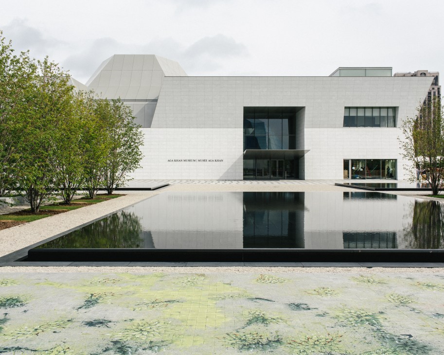 Modern white granite exterior of the Aga Khan Museum with reflecting pool and landscaping.