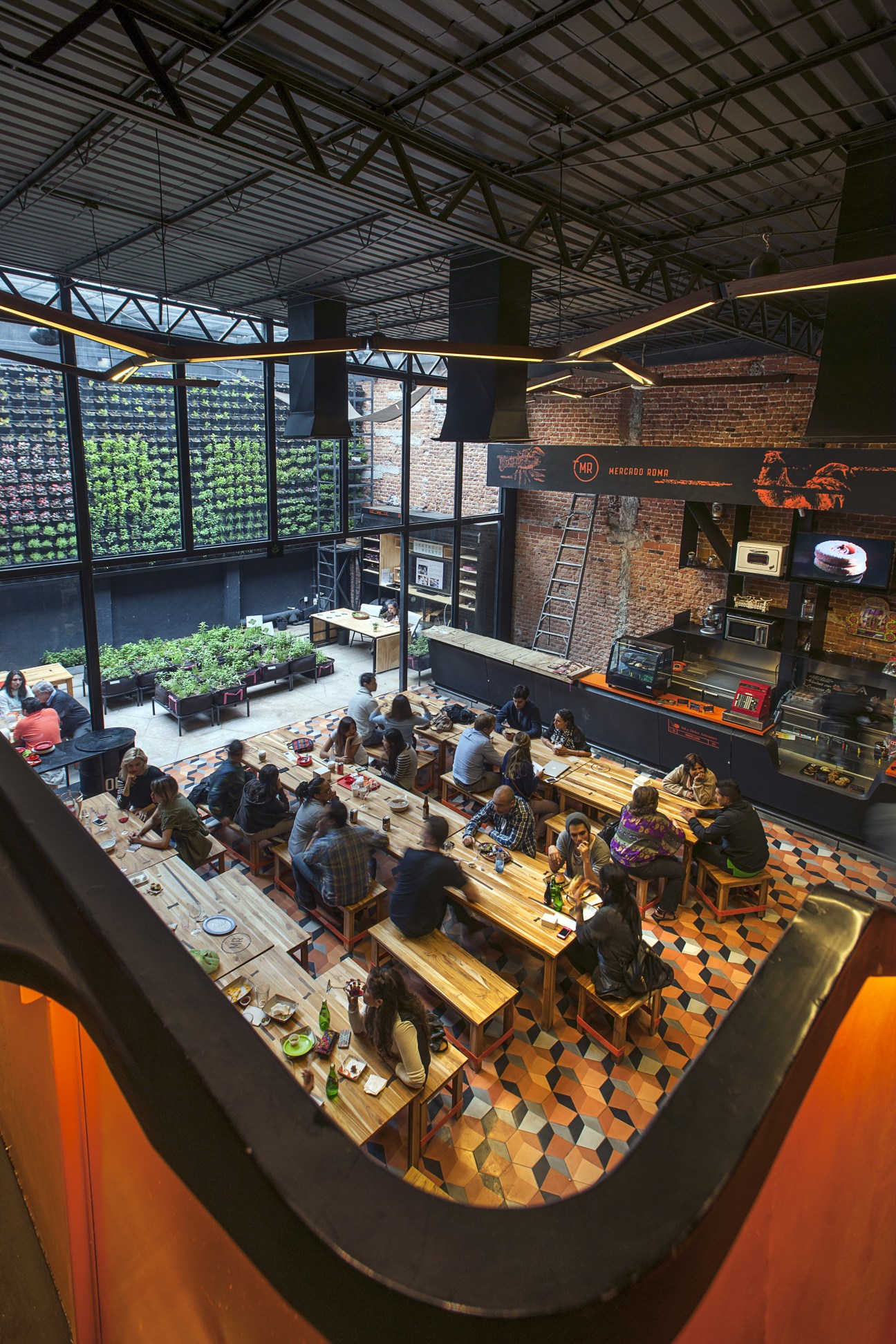 Overhead view of Mercado Roma with diners at wooden tables, vertical gardens, and industrial ceiling.