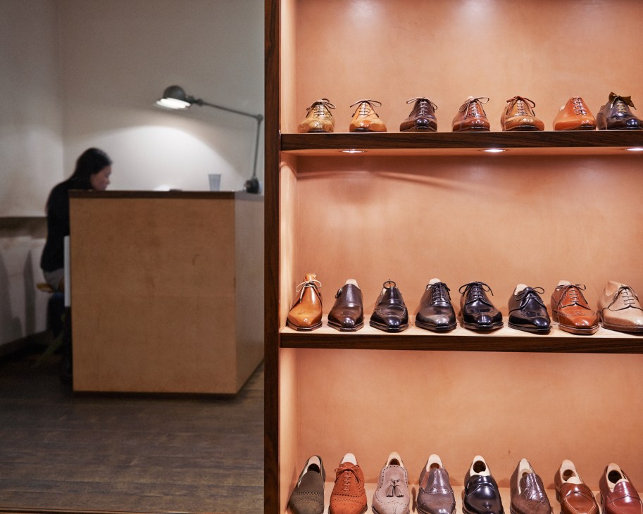Bespoke leather shoes displayed on illuminated shelves in Hidetaka Fukaya's Florence workshop.