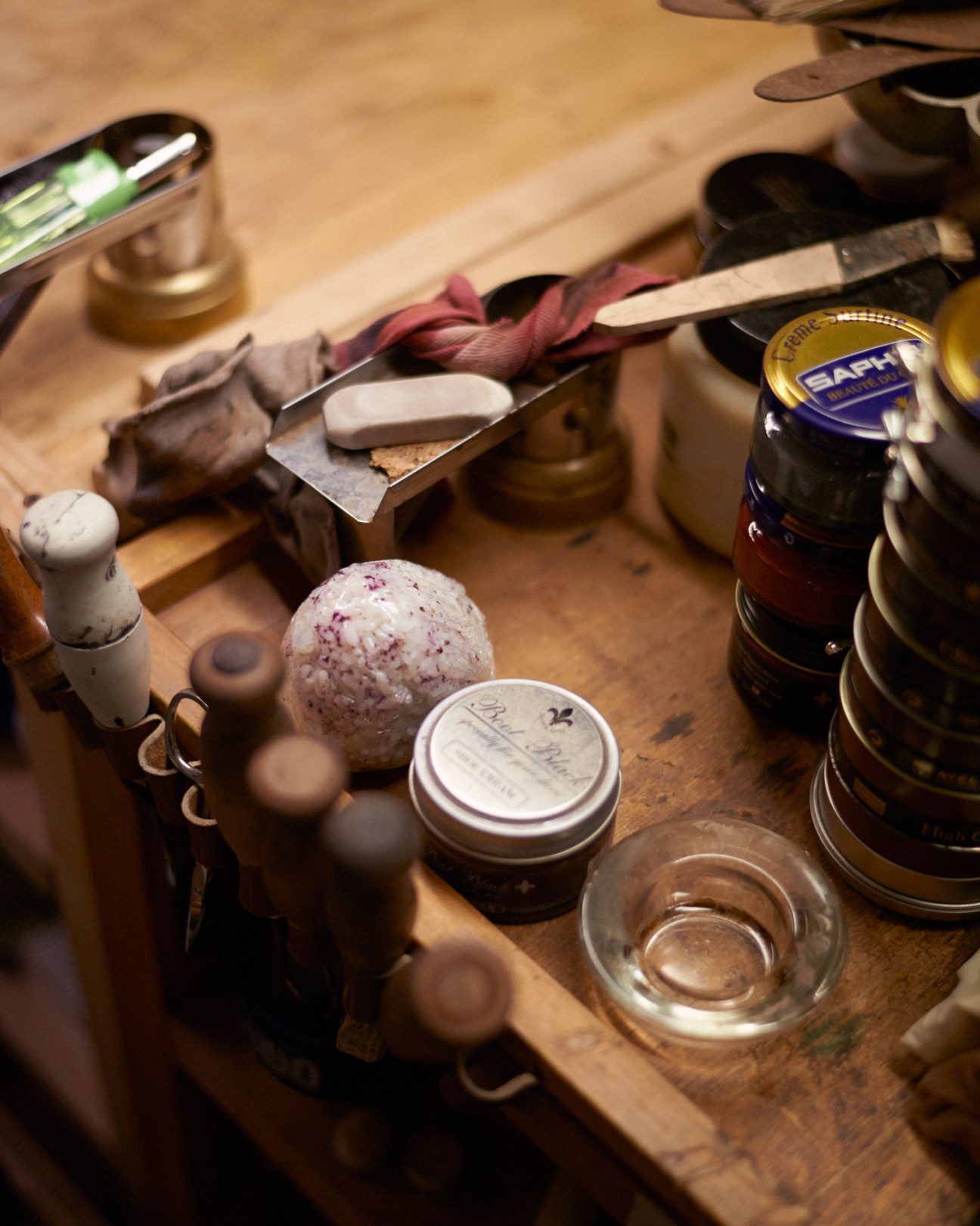 A shoemaker's workbench with tools, leather scraps, a rice ball, and craft materials.