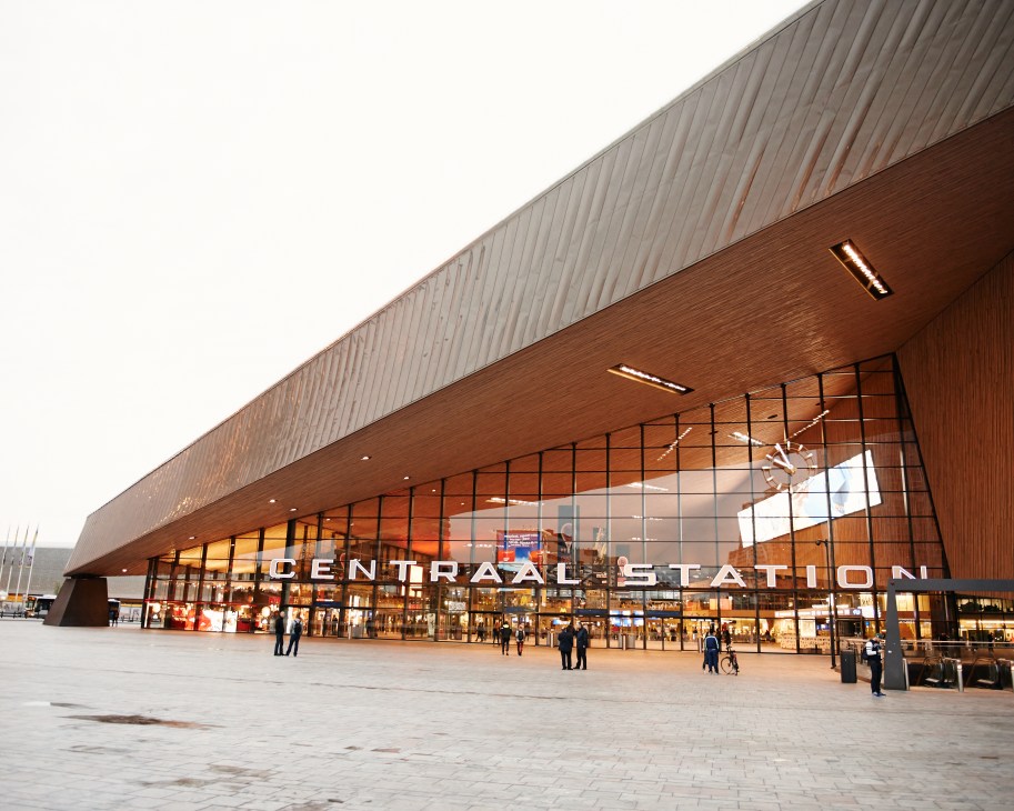 Rotterdam's Centraal Station, a modern building with copper-coloured facade and angular design, with people in the plaza below.