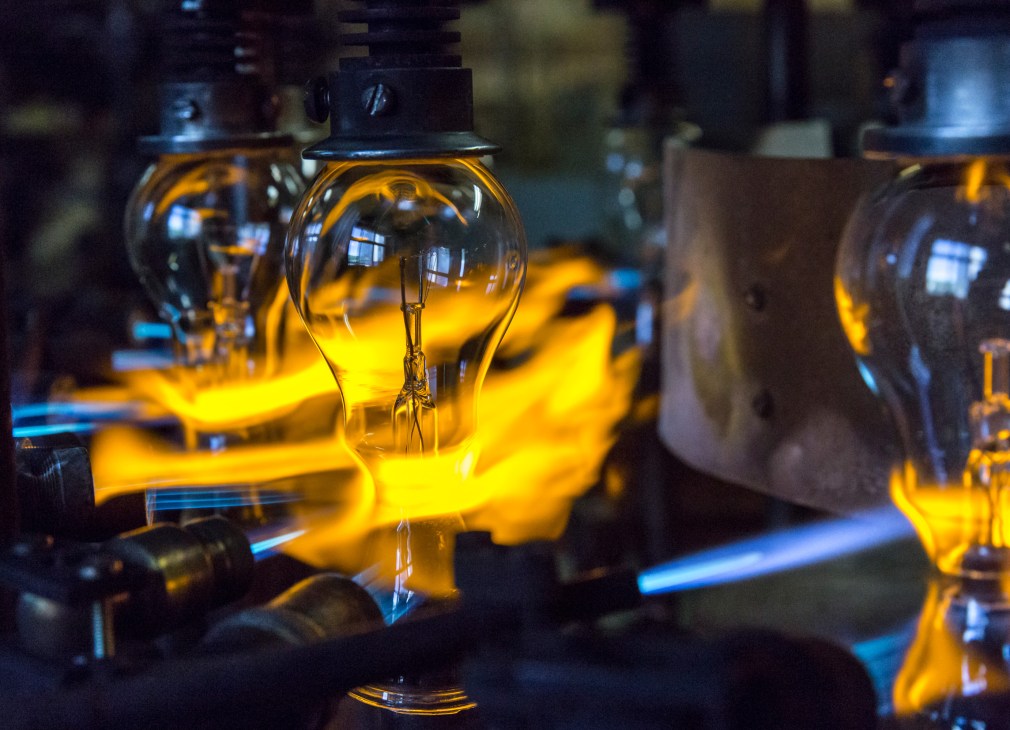 Incandescent bulbs being sealed with blue flames during manufacturing at Righi Licht factory.