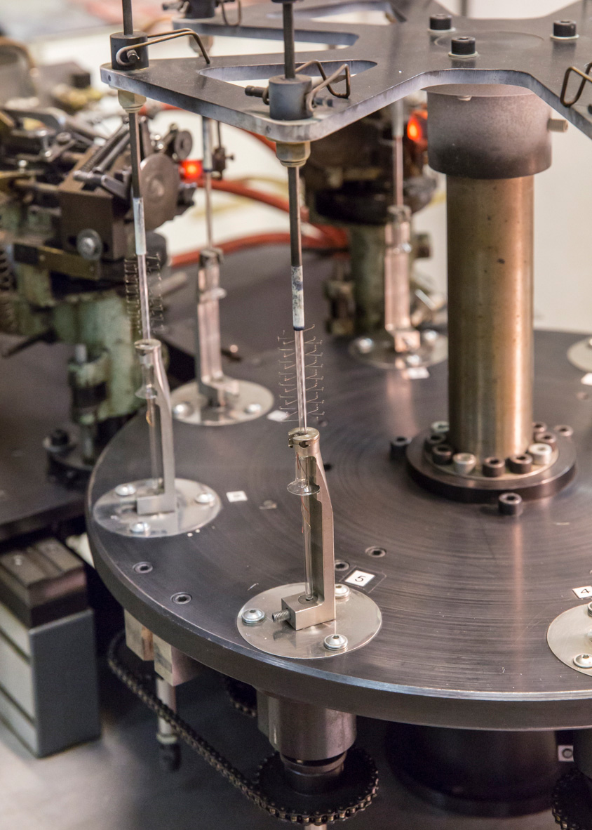 Close-up of delicate coiled tungsten filaments suspended in manufacturing machinery at Righi Licht.