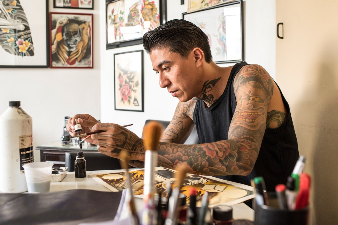 Tattoo artist Jeizel Seidy working on a traditional Japanese design at his studio desk.