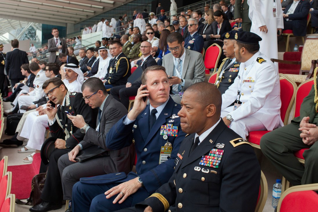 Military dignitaries and officials in uniforms and formal attire seated in bleachers at Idex opening ceremony.