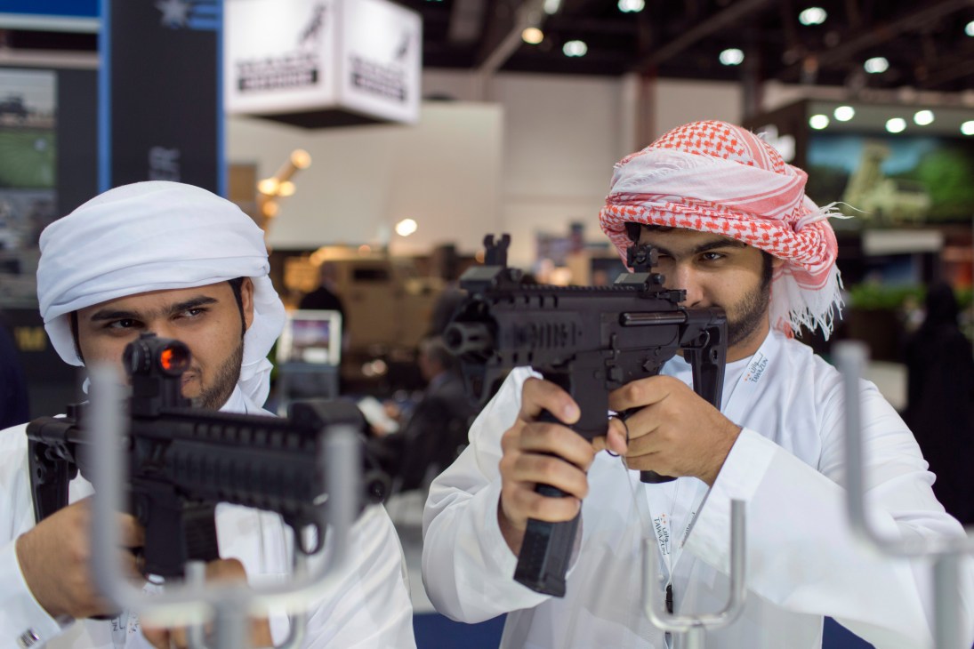Two men in traditional Middle Eastern dress examine Sig Sauer assault rifles at the Idex defence exhibition.