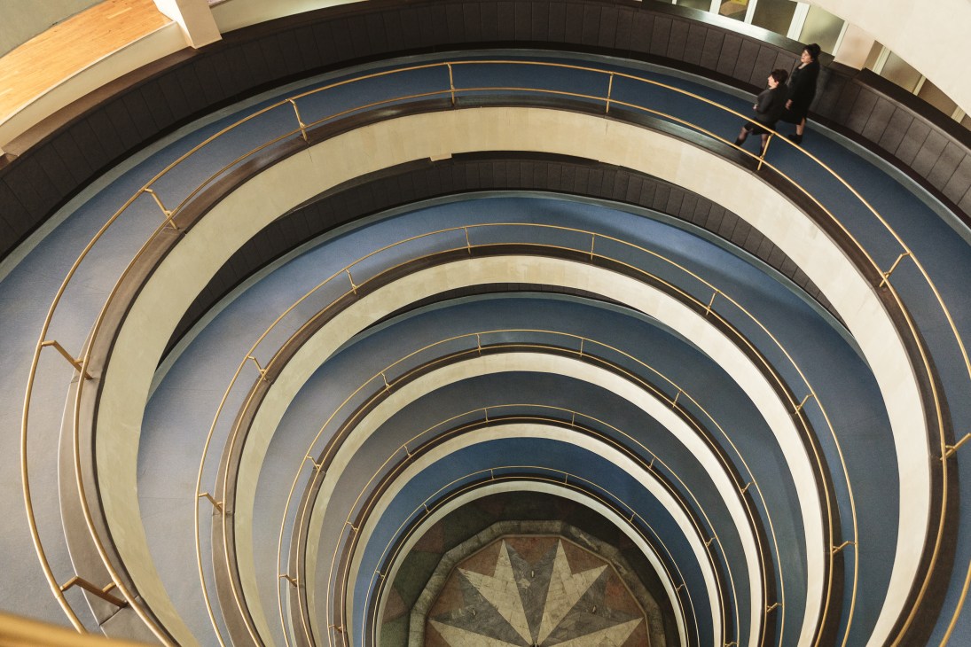 Spiral staircase with concentric rings of blue and cream-coloured bands and brass railings in a Soviet-era ministry building.