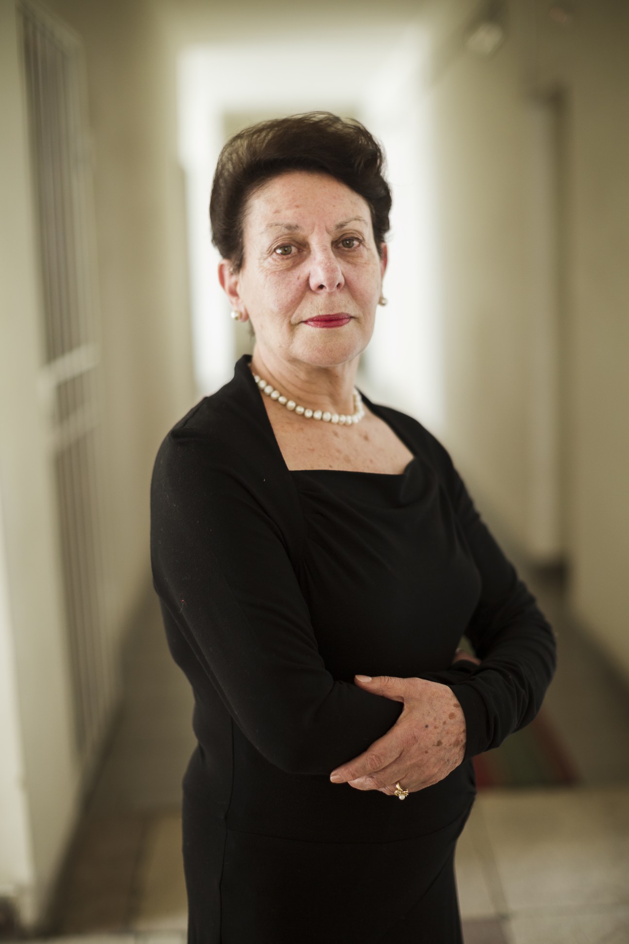 Portrait of Anahit Bakhshyan, opposition politician, in a hallway wearing black and pearls.