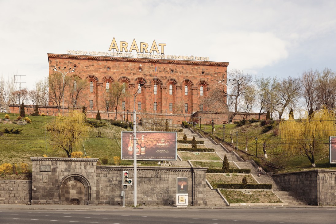 Red brick building with 'Ararat' signage and Armenian text, surrounded by manicured grounds and bare trees.