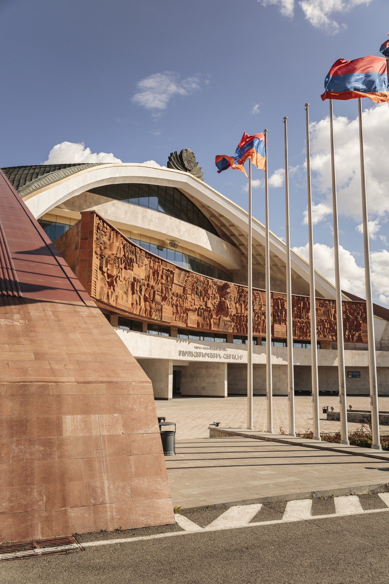 Karen Demirchyan Sports and Concert Complex with Armenian flags and carved relief facade.