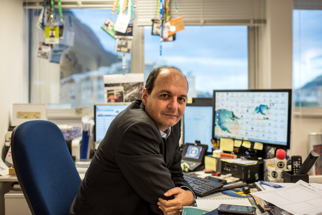 Mariano Boni, executive director of journalism at Globo, sits at his desk surrounded by computer monitors in his office with a mountain view.