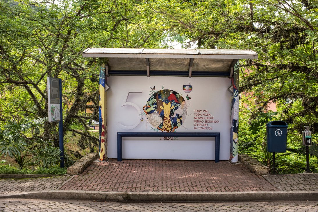 Globo-branded bus stop shelter with 50th anniversary artwork featuring wildlife and Portuguese text in Rio de Janeiro.