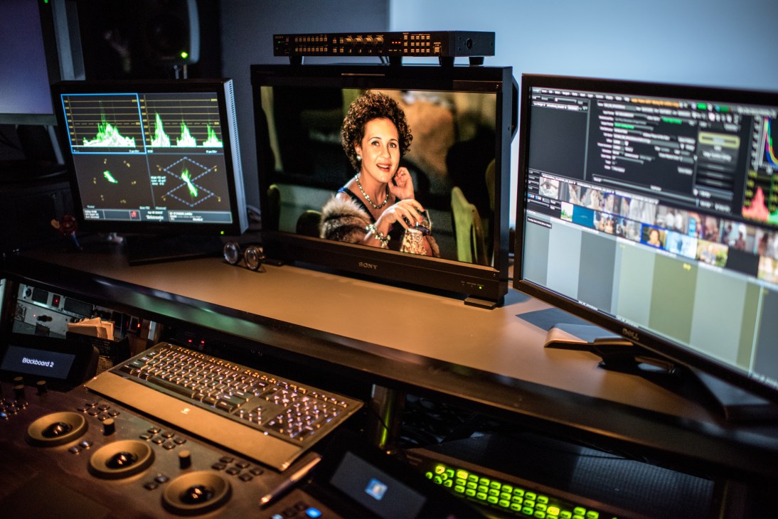 Post-production editing station with multiple monitors displaying video content and audio waveforms.