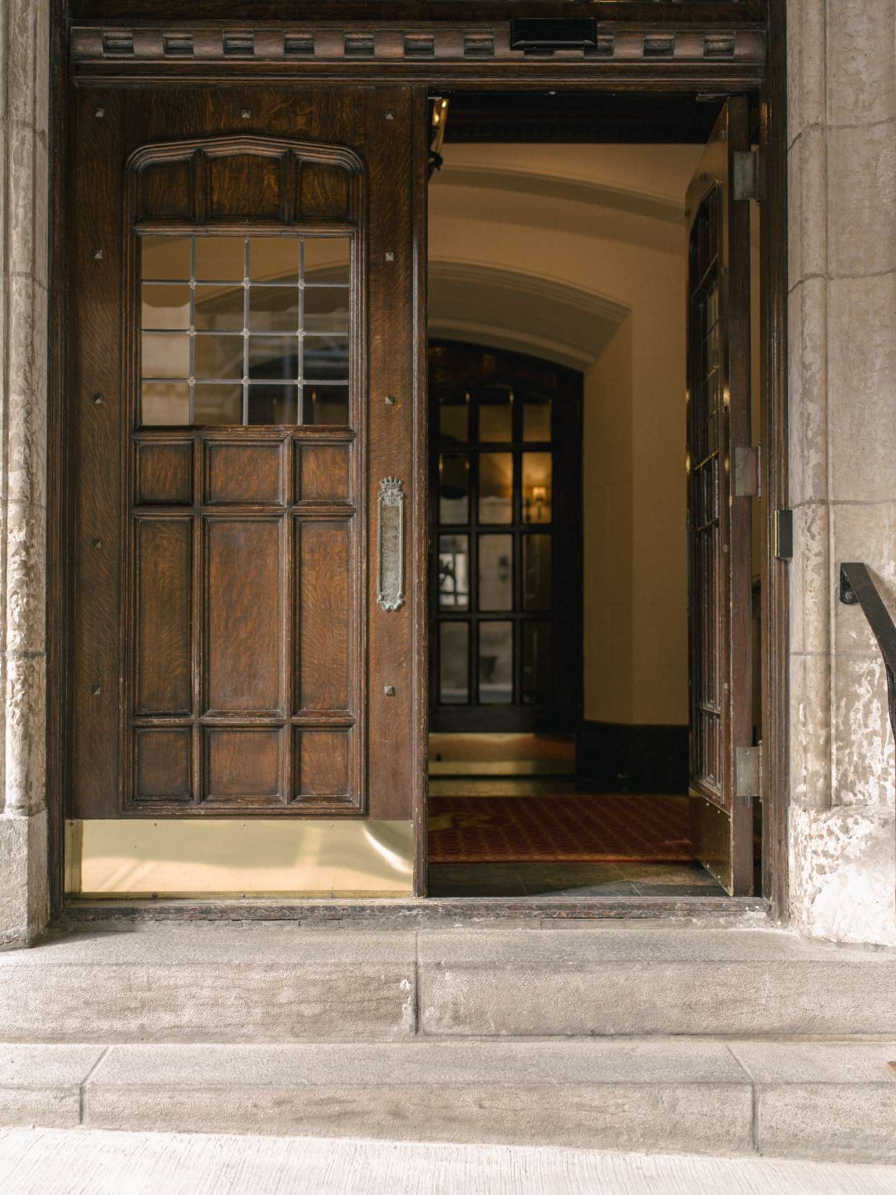 Wooden entrance door to the Chateau apartment building with glass panes and ornamental hardware.