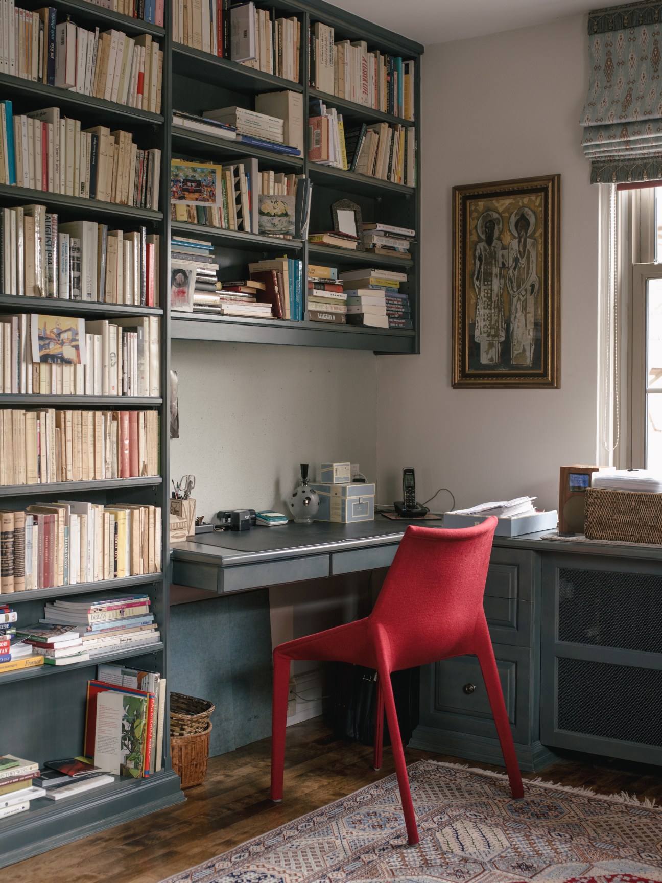 Nicole Brodeur's book-lined office with dark shelving, desk, and red chair in Montreal apartment.