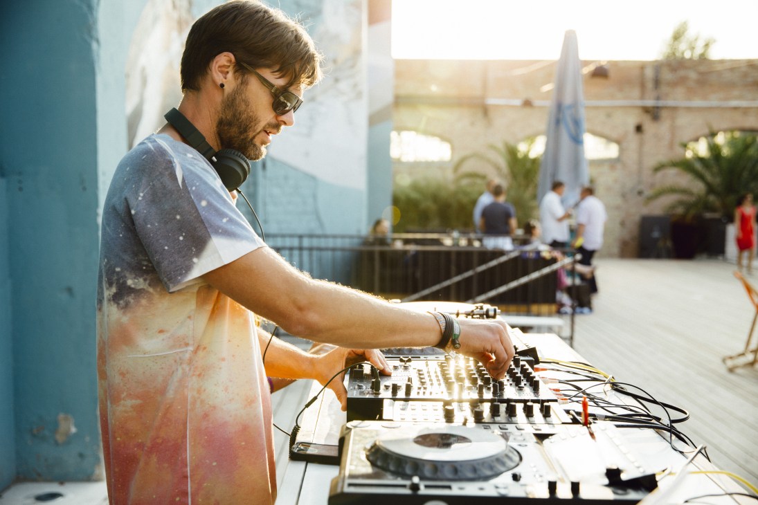 DJ operating turntables at Haubentaucher pool venue in Berlin during evening hours