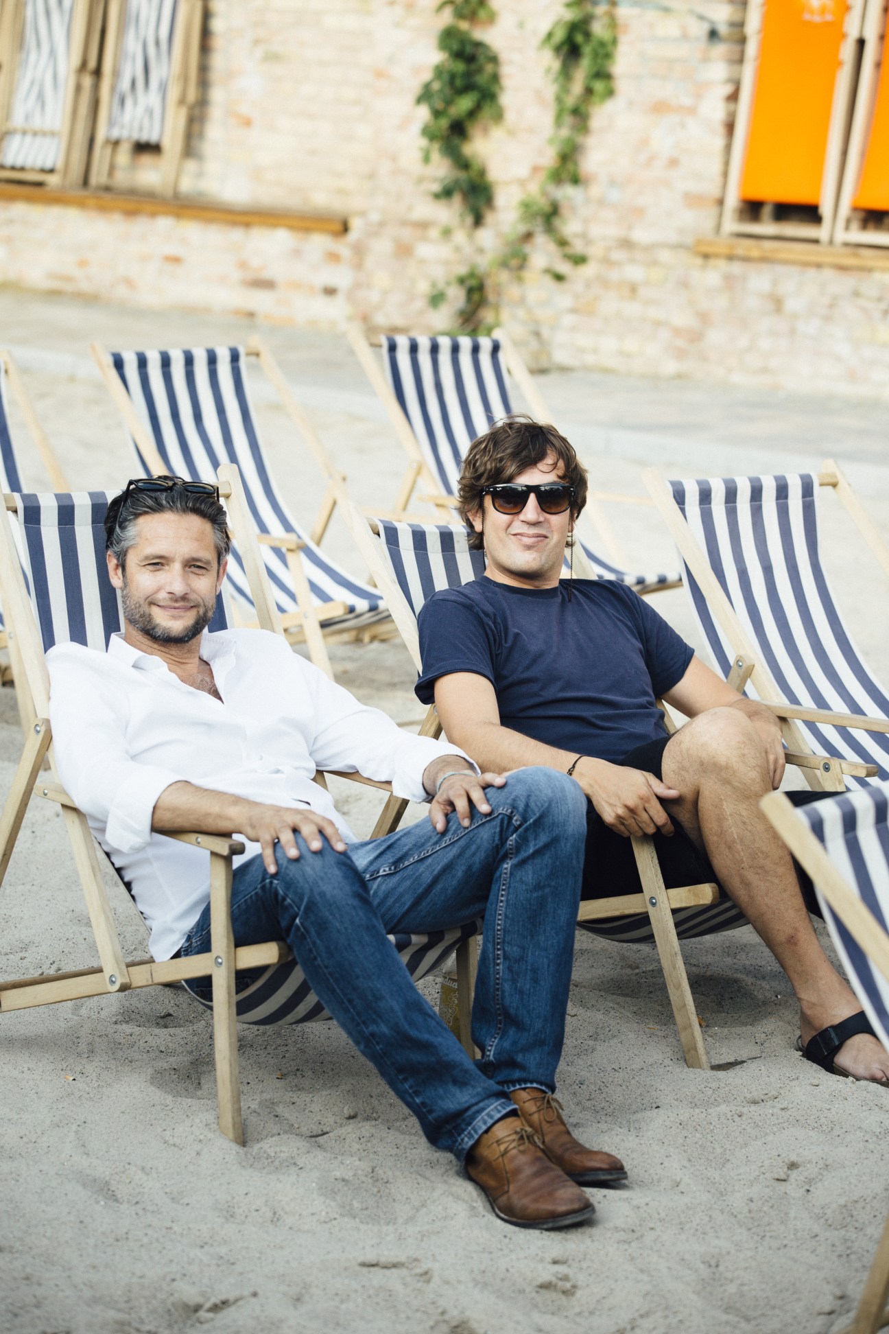 Two men sitting in striped deck chairs at Haubentaucher pool in Berlin