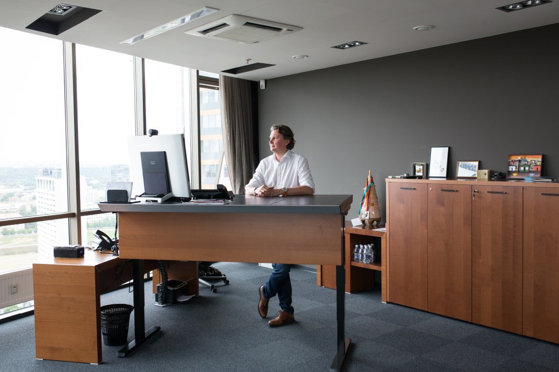 Kestutis Sliuzas, CEO of Teo, seated at his wooden desk in a high-rise office with floor-to-ceiling windows overlooking Vilnius.