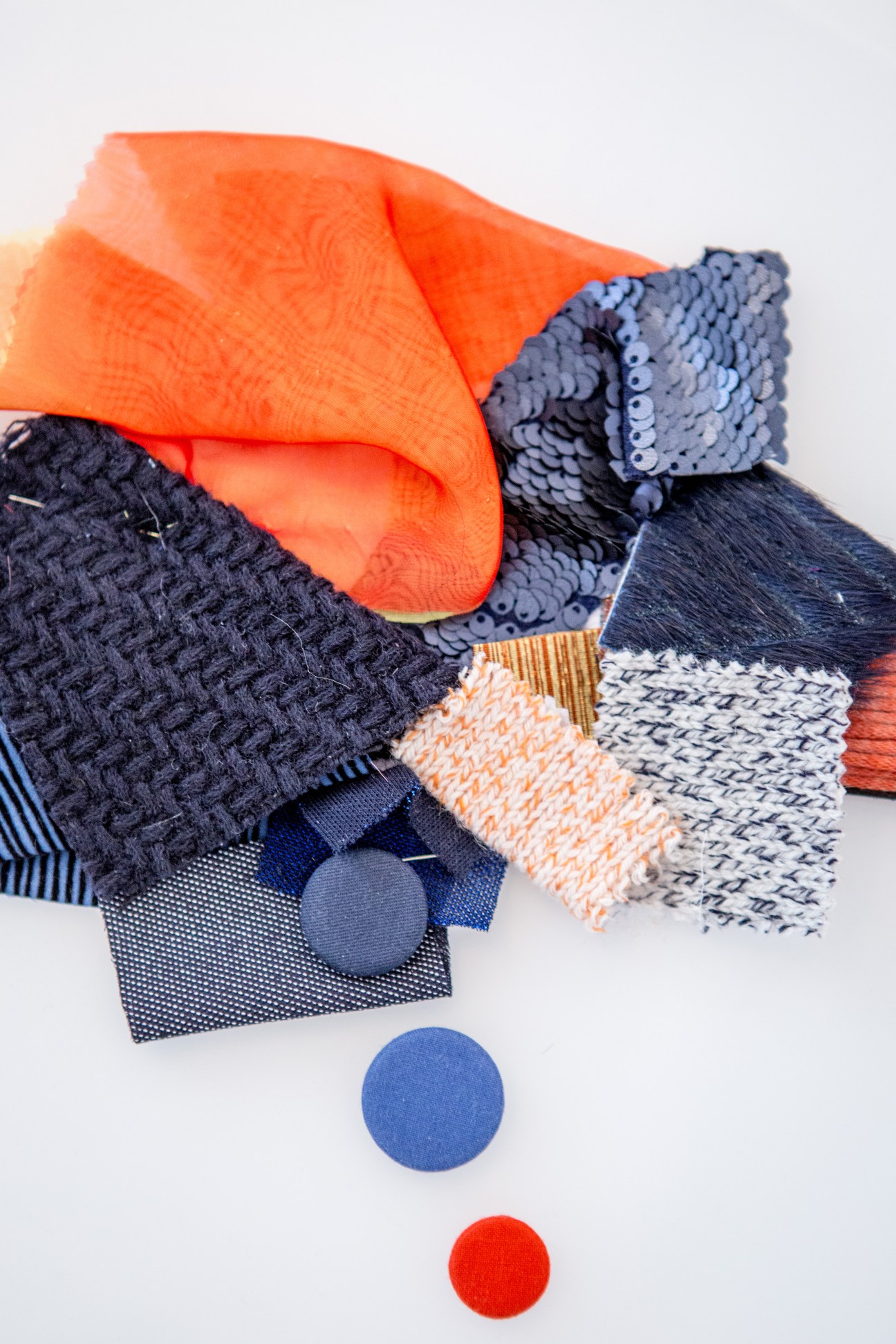 Colorful fabric samples from Courrèges SS16 collection including orange, navy, and patterned materials with matching buttons.