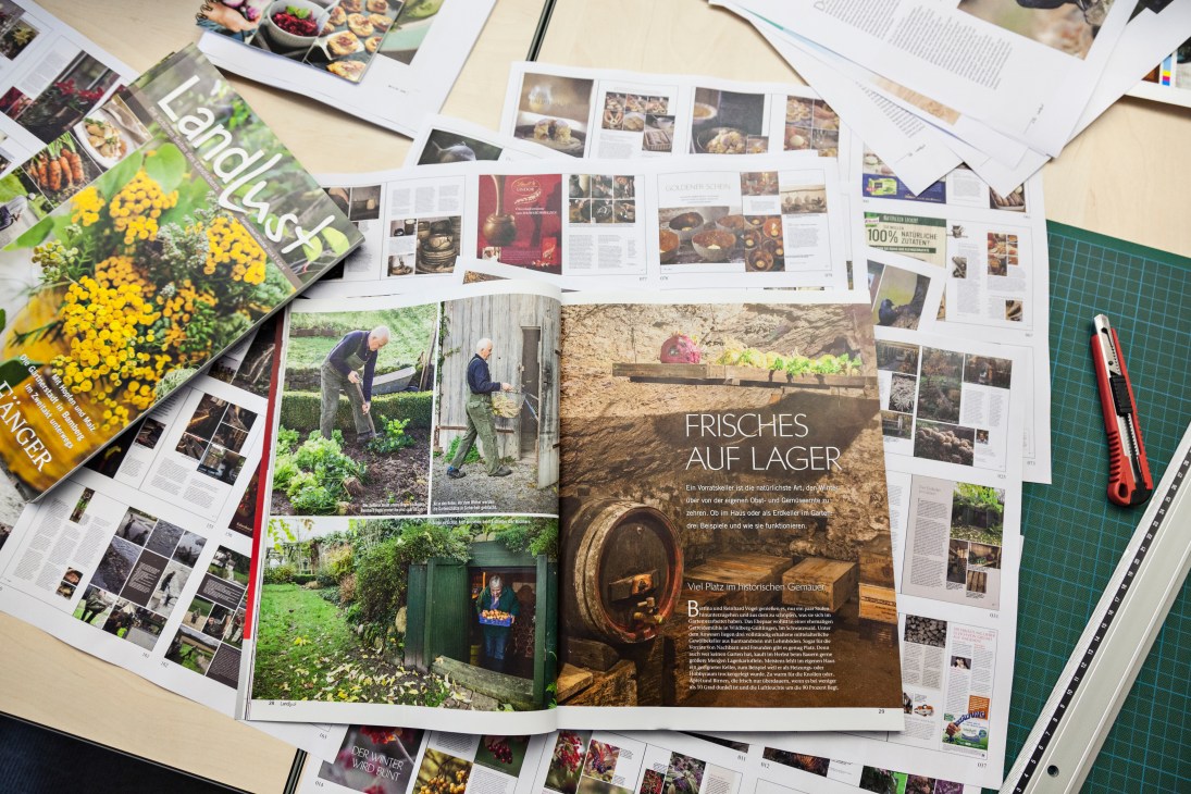 Copies of Landlust magazine spread across a desk alongside other publications and design materials.