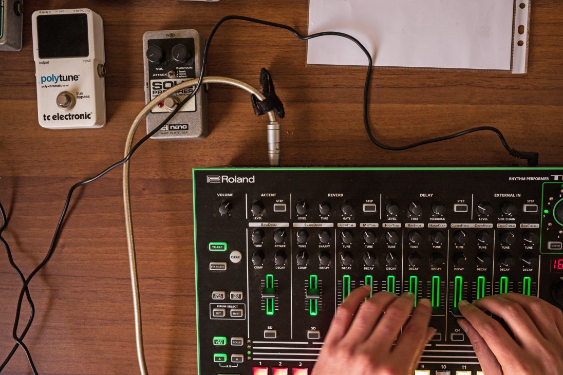 Hands adjusting controls on a Roland rhythm machine in Dandin's offices.