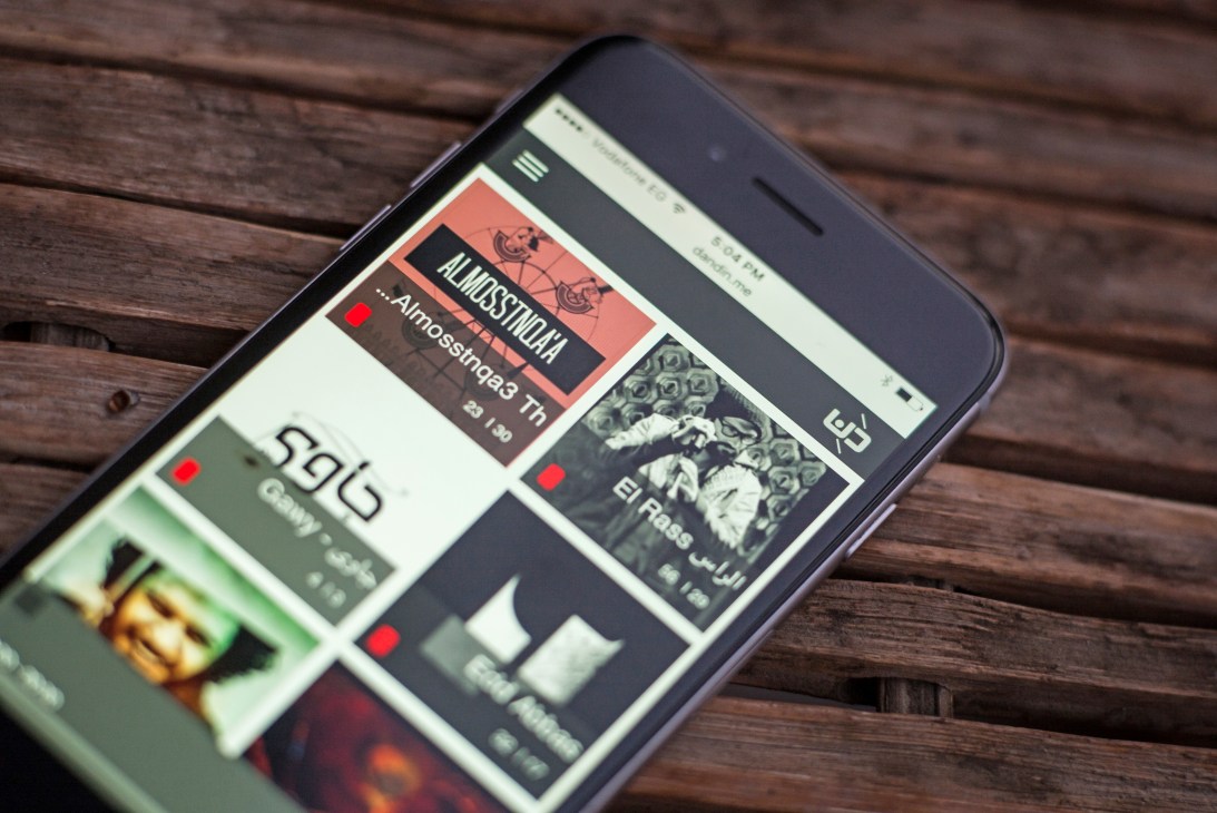 Smartphone displaying the Dandin audio platform interface with multiple music tracks and artist listings.
