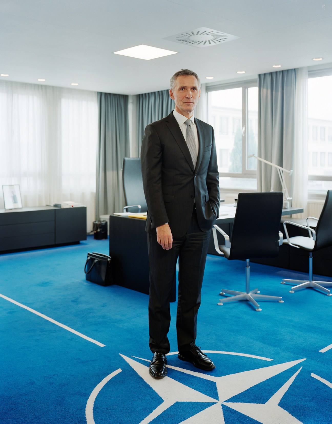 Jens Stoltenberg, NATO secretary-general, stands in his modern office with blue carpet featuring the NATO star logo.
