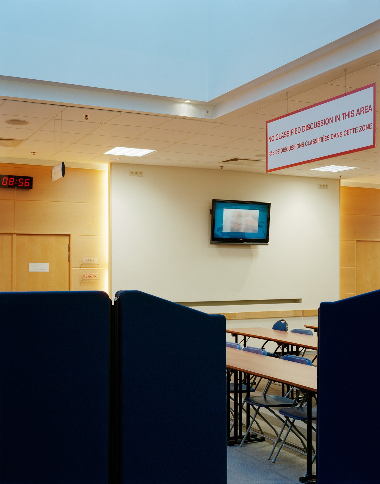 NATO briefing room with security sign warning against classified discussion and vintage security poster.
