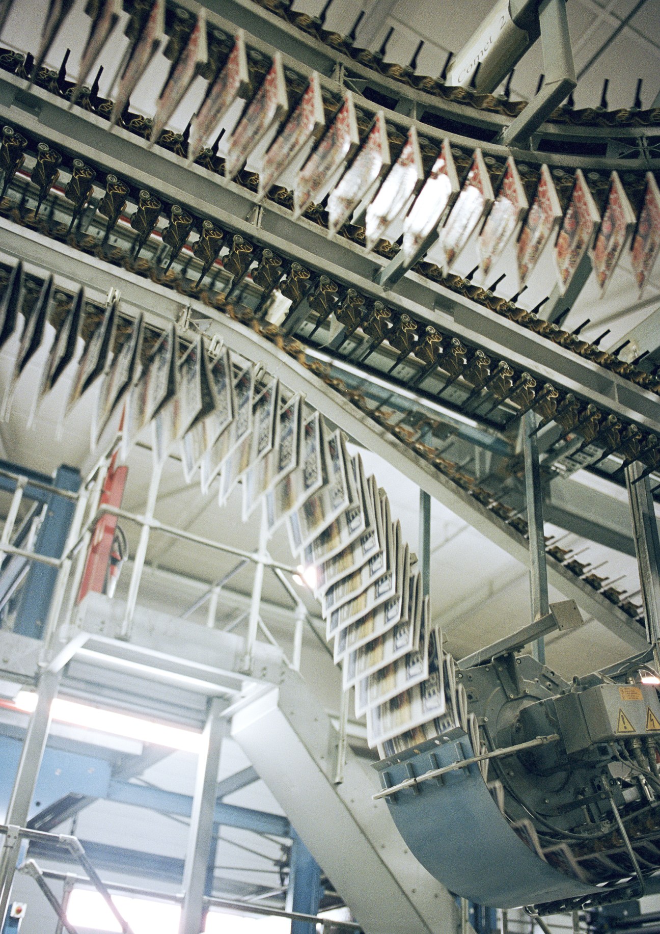 Newspapers hanging from conveyor lines at a printing facility