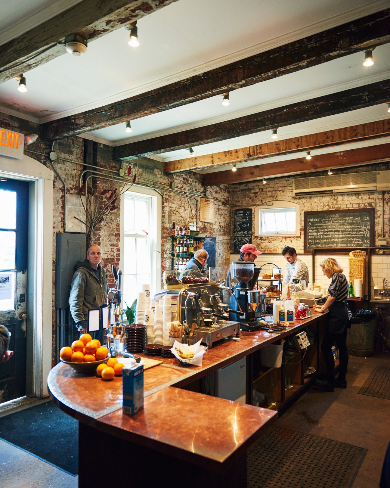 Interior of Rubi's cafe in Great Barrington with customers at counter and exposed brick walls.