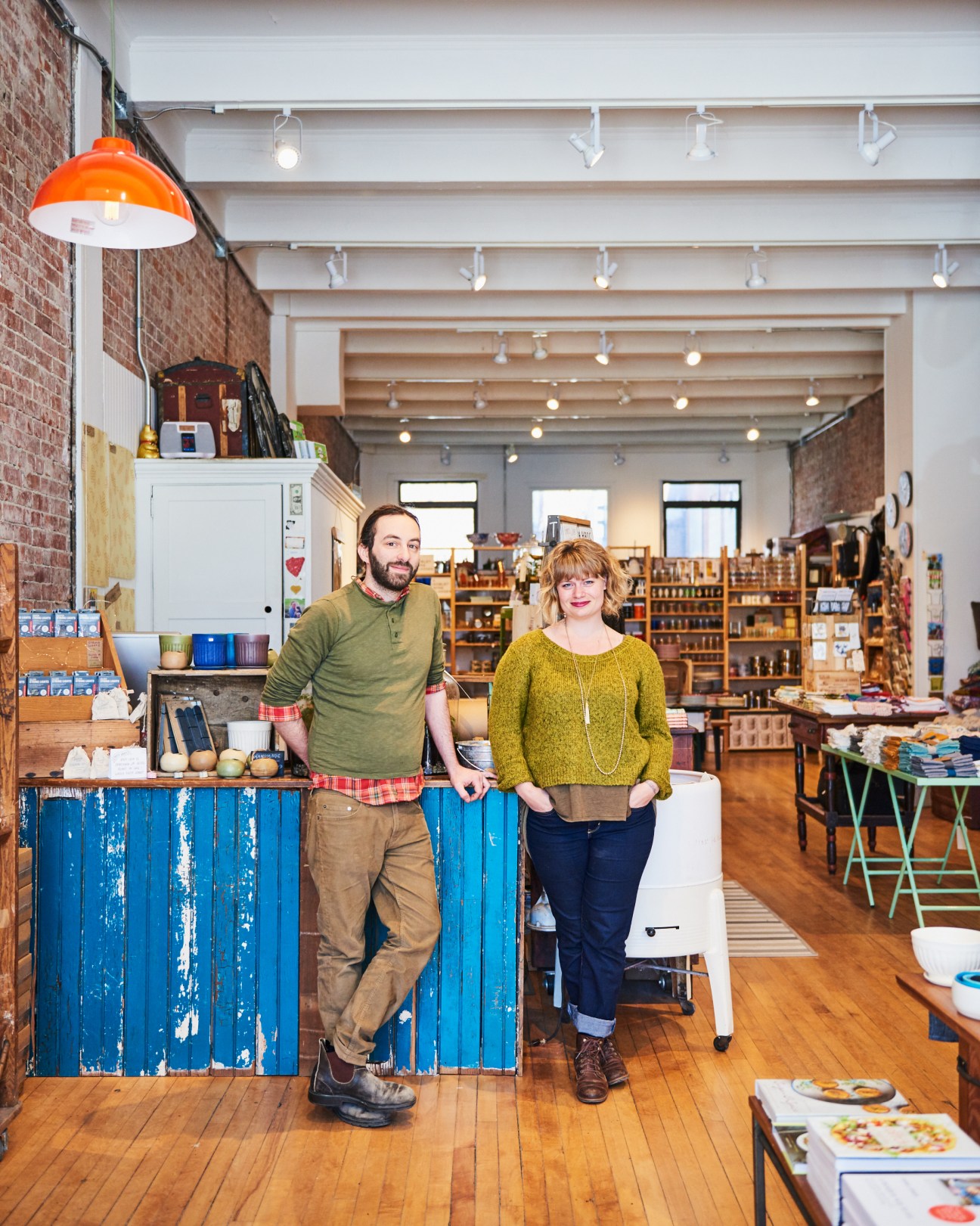 Man and woman standing behind blue counter in One Mercantile boutique shop in Great Barrington