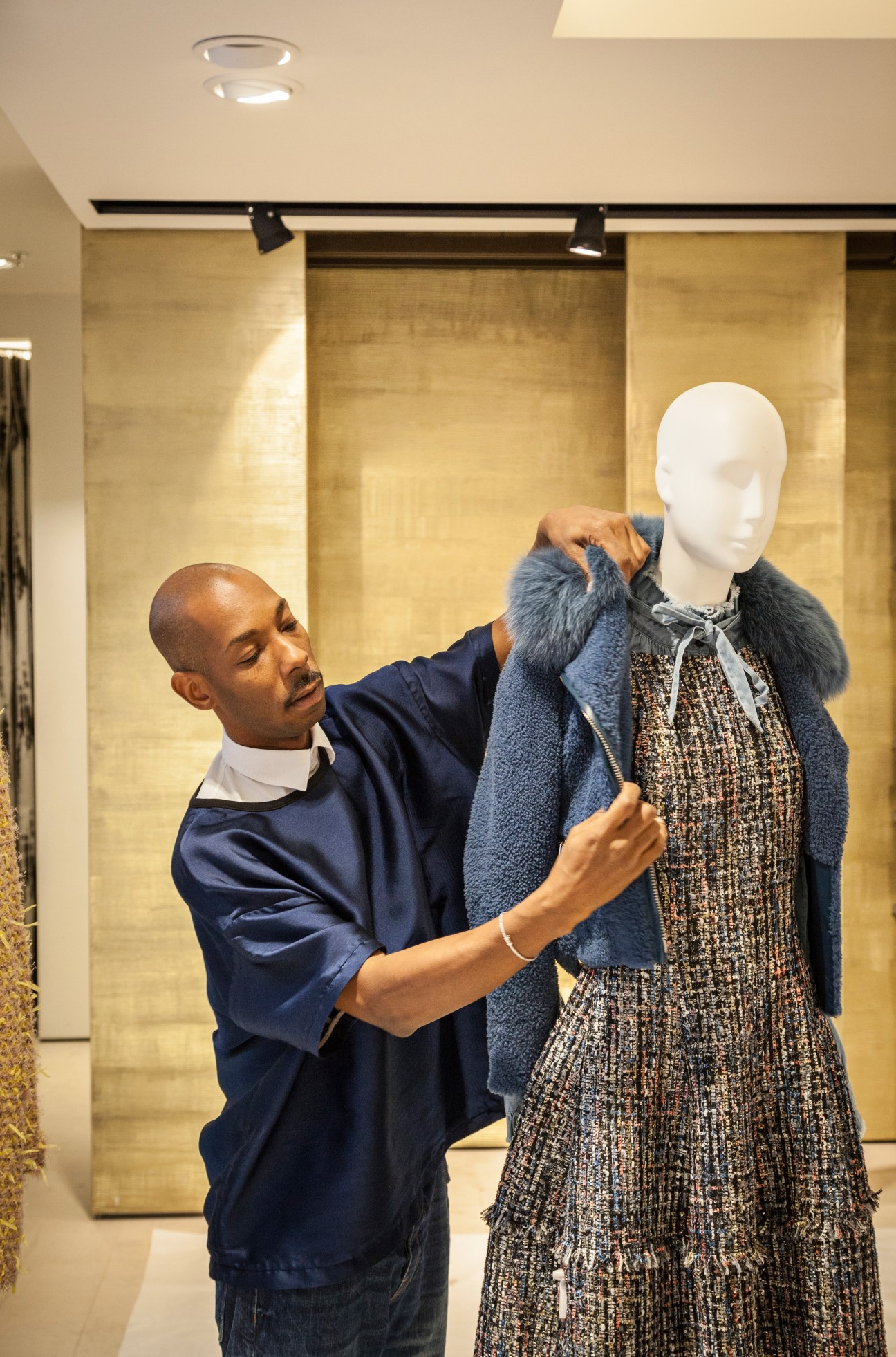 An Engelhorn employee adjusts a blue cardigan on a mannequin displaying fashion in the store.