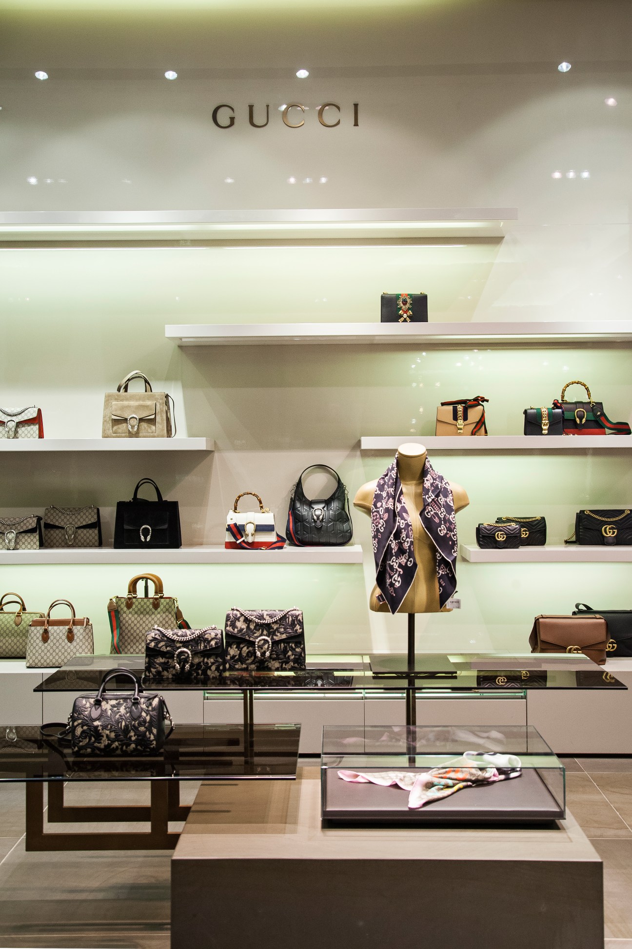 Gucci luxury handbag and accessories display at Engelhorn department store with illuminated shelving.