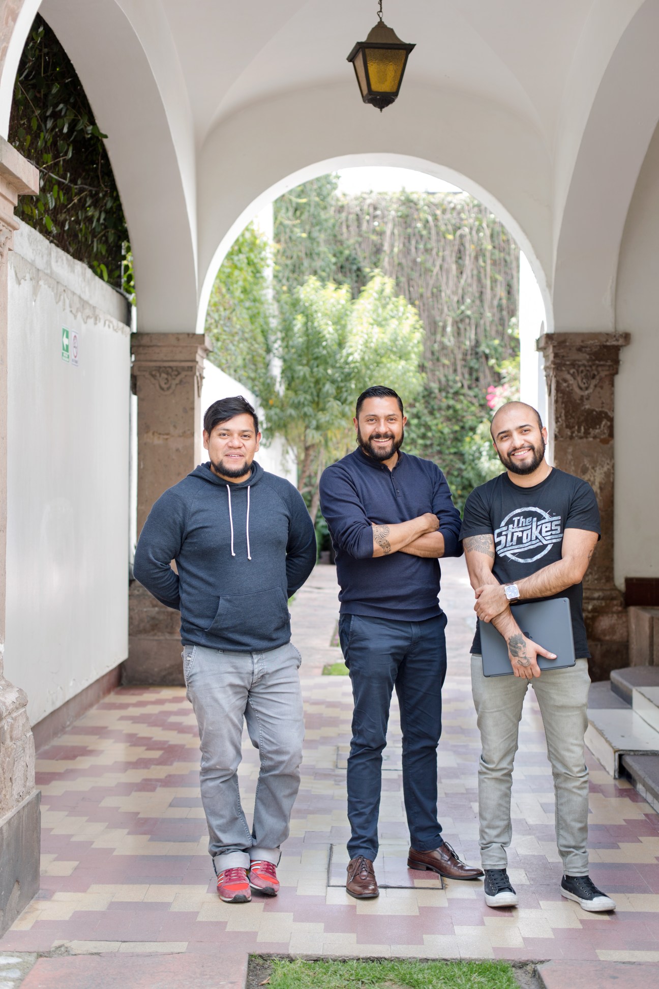 Three men standing in an arched colonnade at Anónimo advertising agency in Mexico City.