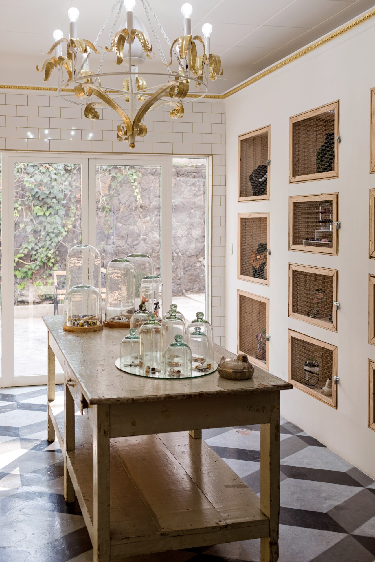 Interior of Common People boutique showing display table with glass cloches and botanical specimens under a brass chandelier.