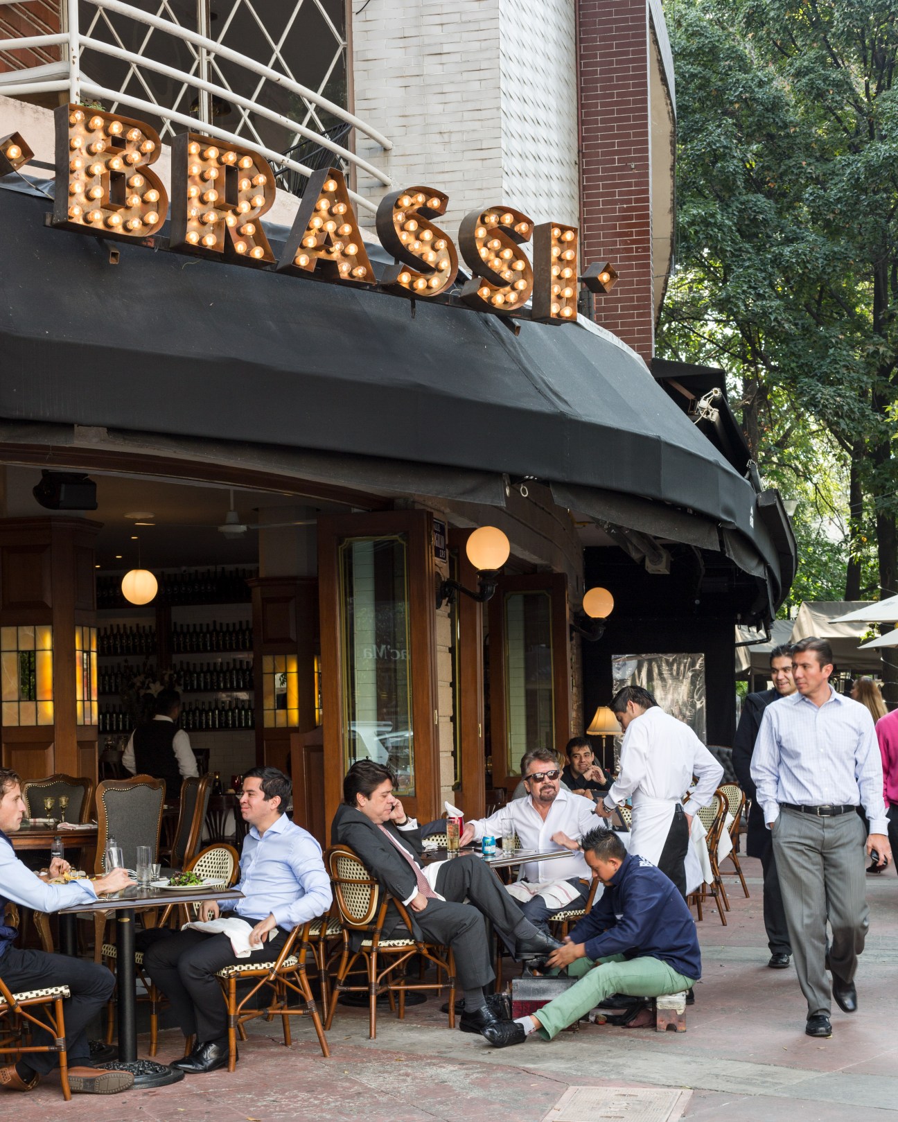 Diners seated at outdoor tables beneath the illuminated Brassi restaurant sign in Polanquito.