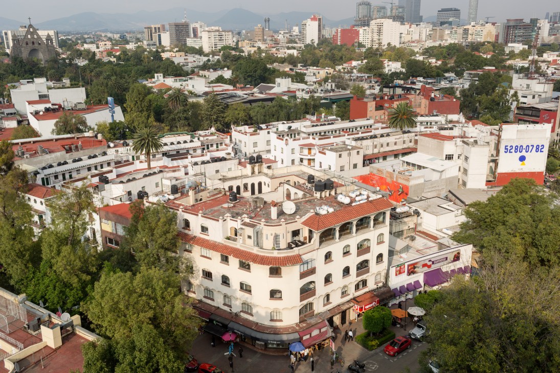 Aerial view of Polanquito neighbourhood in Mexico City showing art deco and mid-century buildings with red roofs and mountains in the distance.