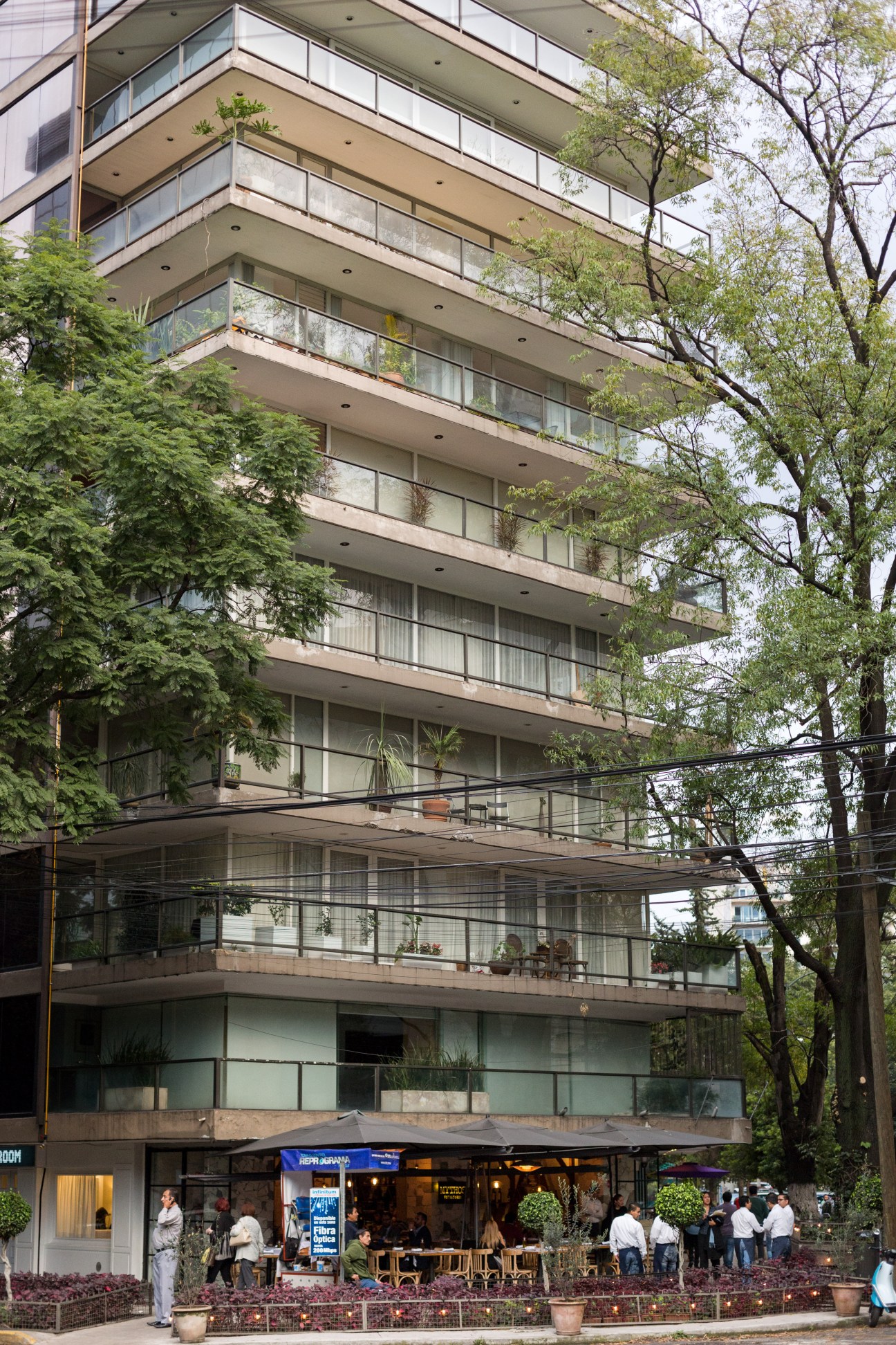 Mid-century modernist apartment building with horizontal balconies surrounded by green trees in Polanquito, Mexico City.