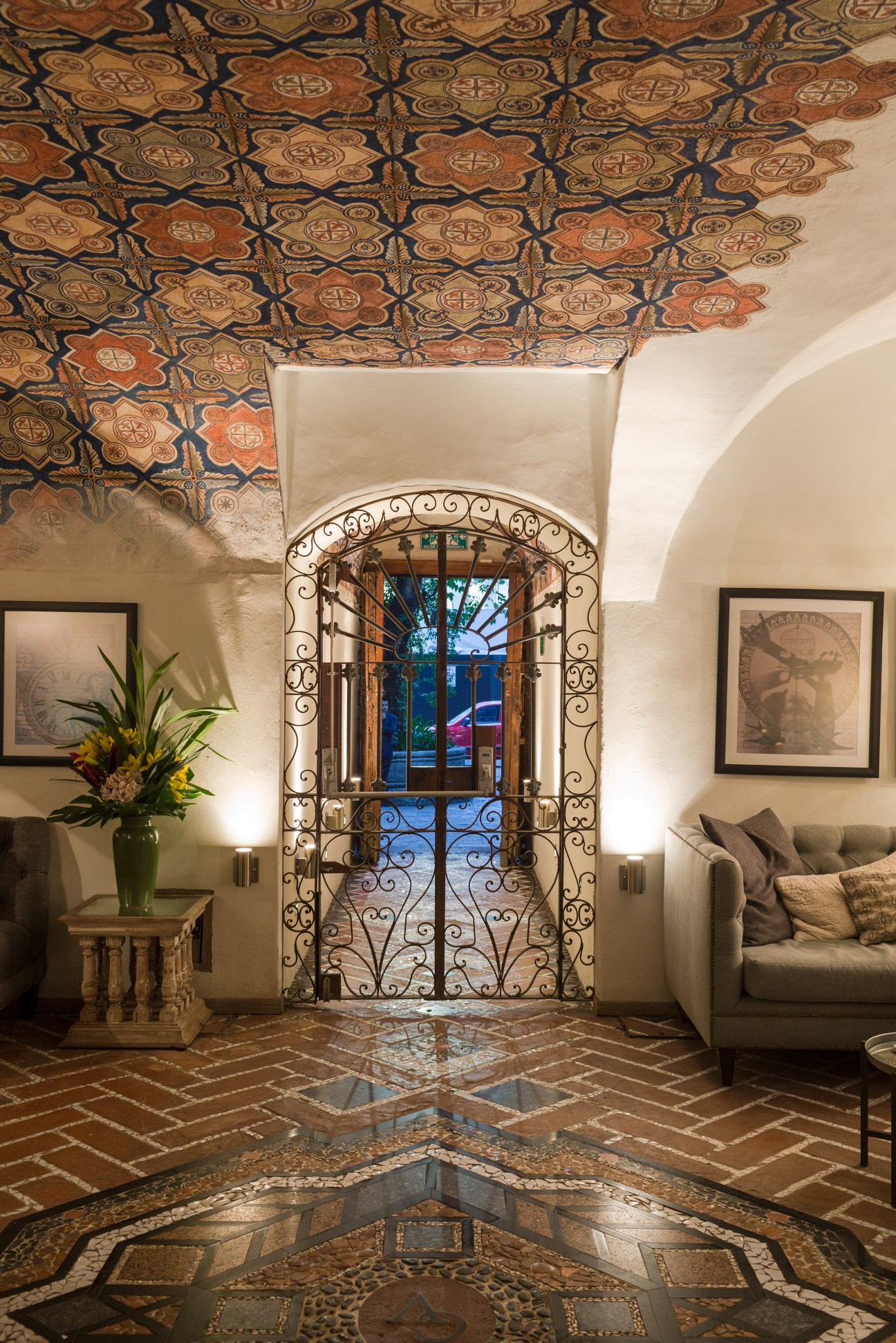 Interior of Busue hotel showing ornate wooden ceiling, arched doorway with wrought iron, terracotta tile floor and cream walls.