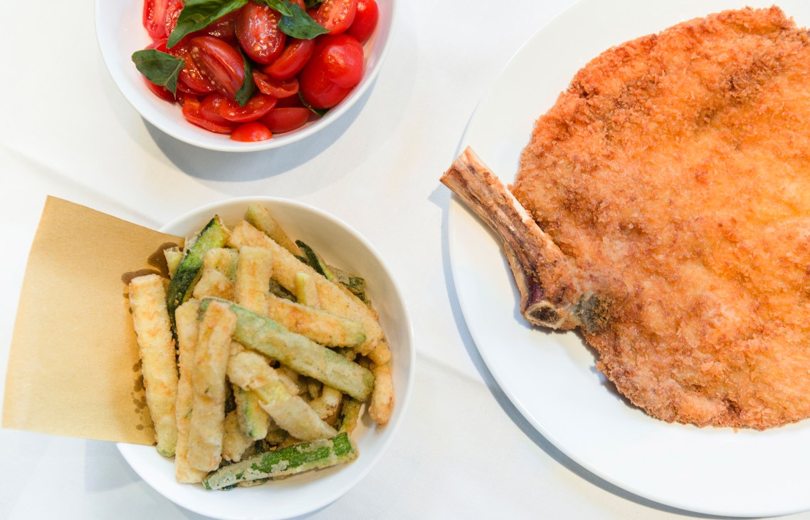 Veal Milanese with breaded cutlet on bone, zucchini fritti, and cherry tomatoes with basil.