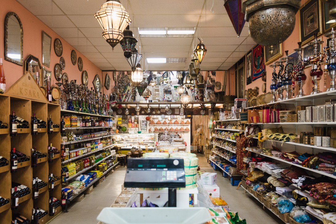 Interior of Harb Lebanese shop with shelves of spices, hanging lanterns, decorative plates on salmon walls.