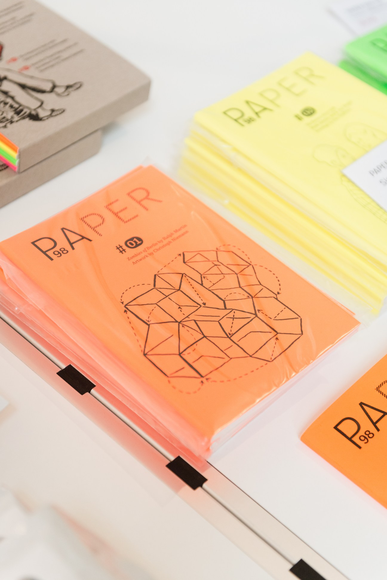 Colorful design publications and notebooks with geometric patterns stacked on a white surface.