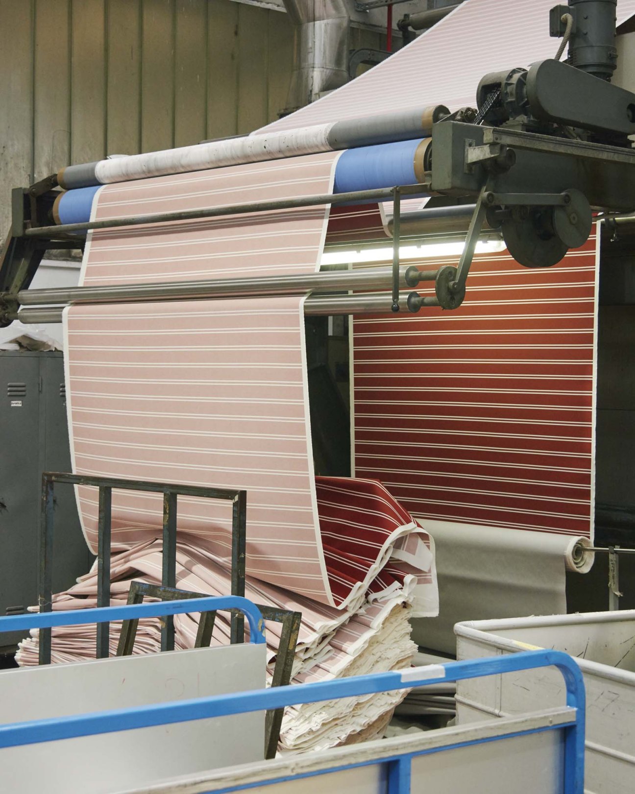 Striped fabric designs in pink, blue, and red tones run through industrial printing machinery at Gentili Mosconi.