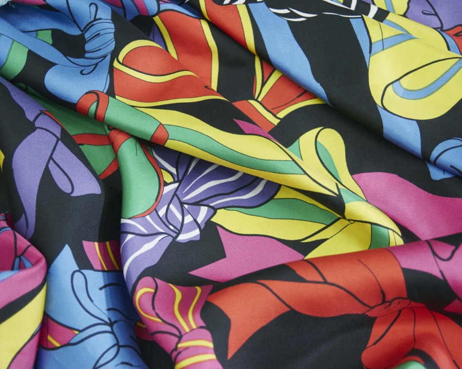 Colorful silk fabric with bold abstract floral design in purple, yellow, blue, pink, and red with black outlines.